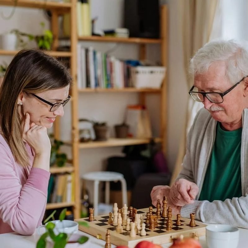 Pflegekraft und Seniorin lachen gemeinsam im Freien